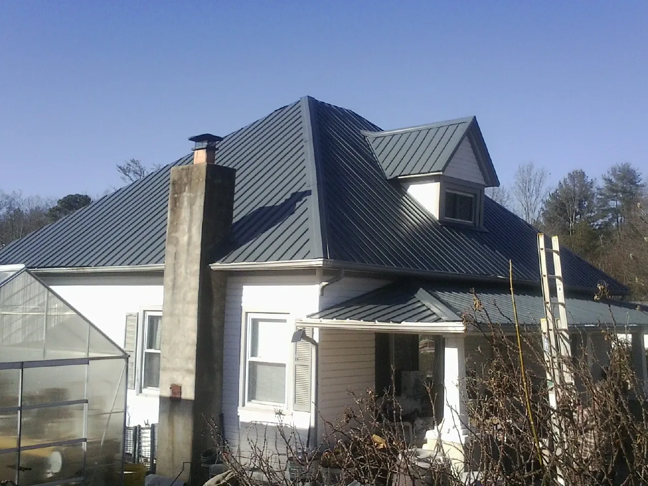 Dark blue standing seam metal roof on a white farmhouse with dormer — Slate & Tile Roof Repair by Roofing Brothers in King Of Prussia