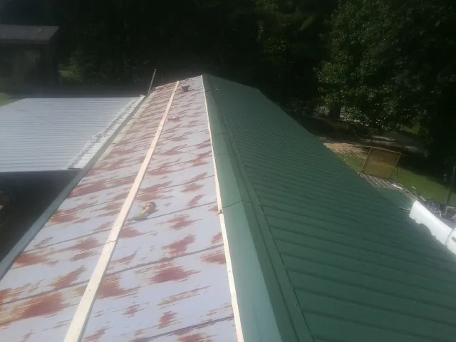 Old rusted panels beside newly installed green metal roofing — Wind Damage Roof Repair by Roofing Brothers in King Of Prussia