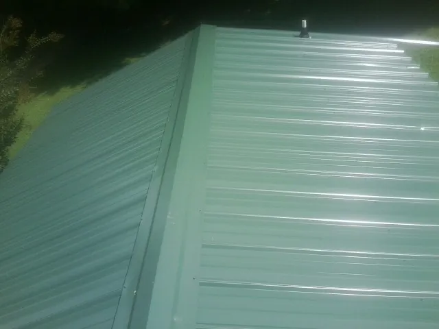 New green metal panels meeting at the ridge of a roof — Flat Roof Repair work by our crew in King Of Prussia